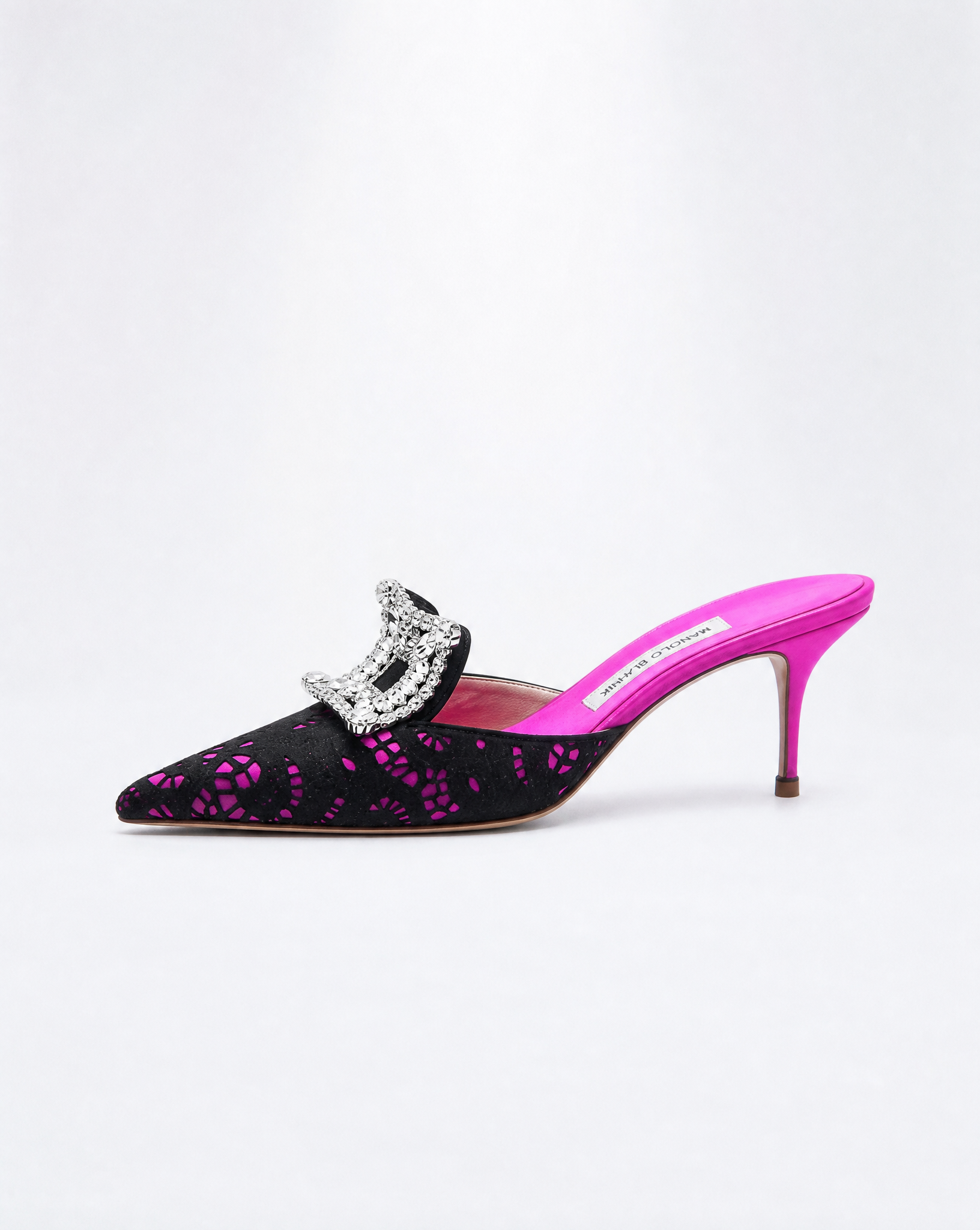 Close-up of the Manolo Blahnik Borli Mules highlighting the intricate lace craftsmanship and the brilliant silver-tone crystal buckle at the vamp.