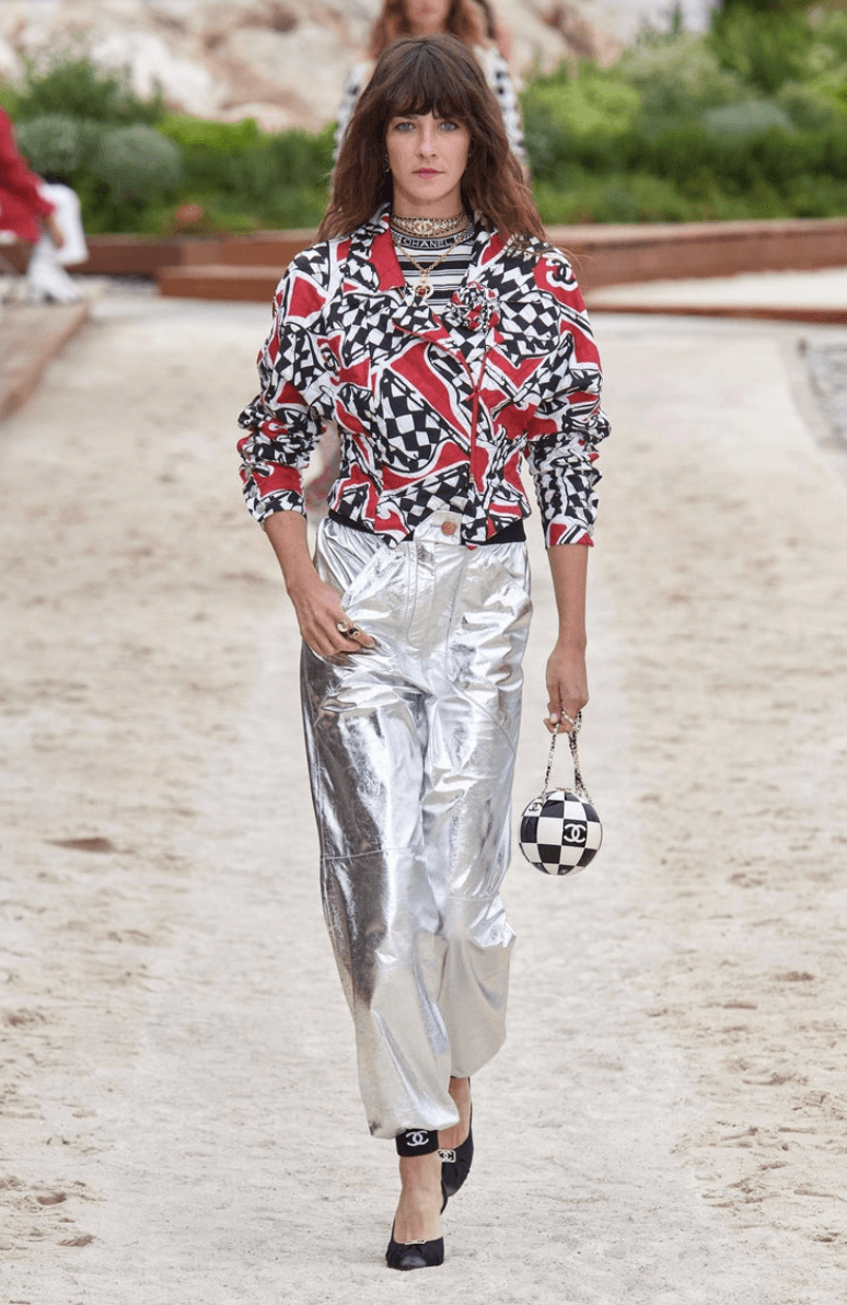Close-up runway of the Chanel logo trim and ribbed knit construction on the black and white striped top.
