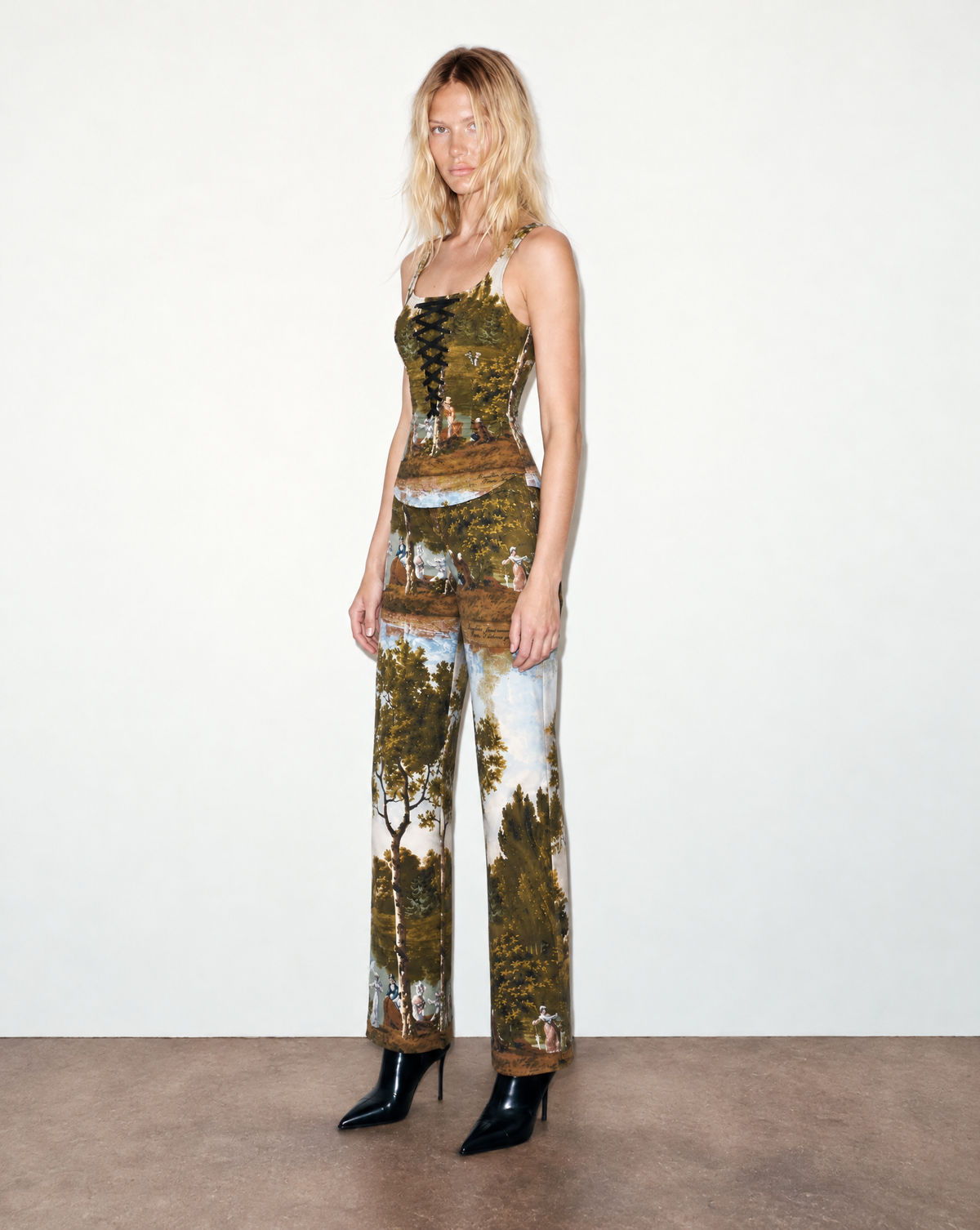 Early 2000s Moschino corset-inspired tank top with a lace-up front and panoramic pastoral landscape print. A collectible piece from Rossella Jardini’s era, available at Mezzanotte Vintage.