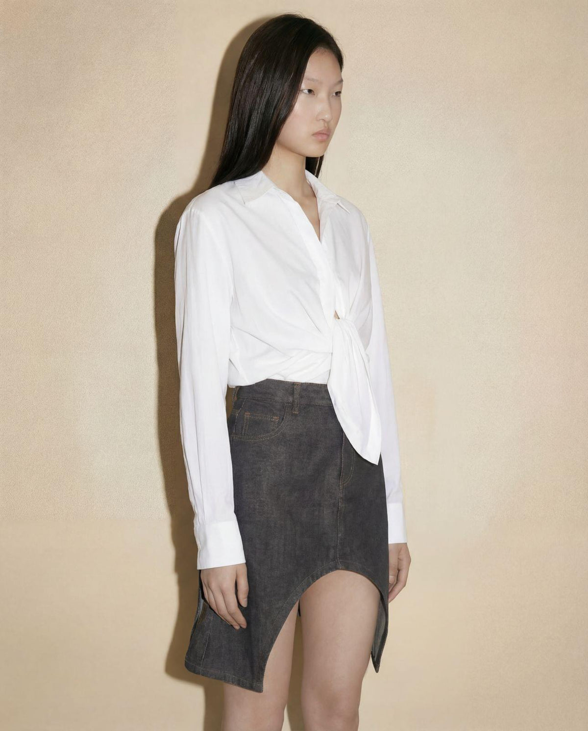Detail of the sculptural asymmetric cut-out hem on the contemporary Courrèges denim mini skirt.