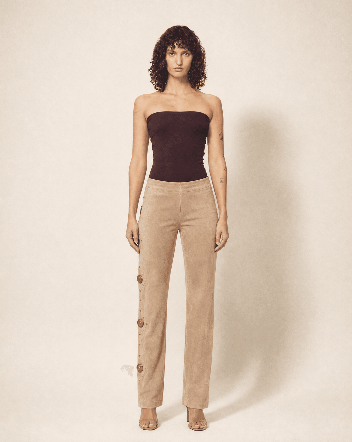 Archival Gianni Versace 1990s suede trousers with Medusa buttons shown full length. Rent in Madrid or buy across Europe at Mezzanotte.