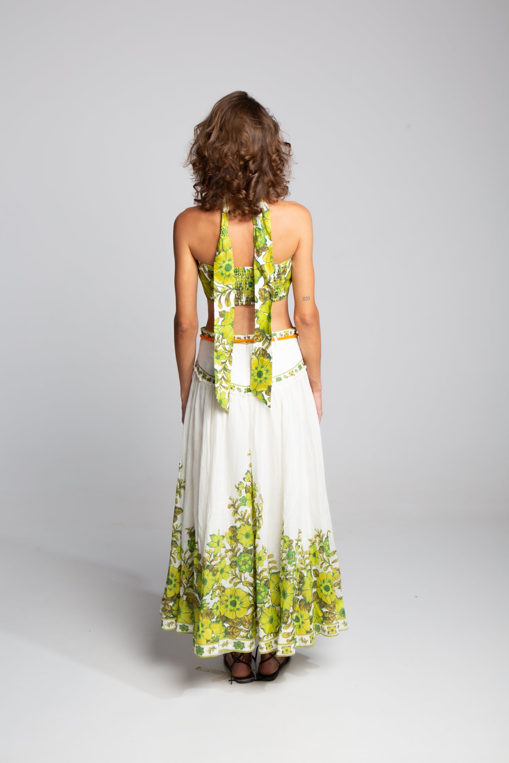 Back view of the Alémais Wallis linen set highlighting the tie-neck fastening and the flowing silhouette of the floral midi skirt.