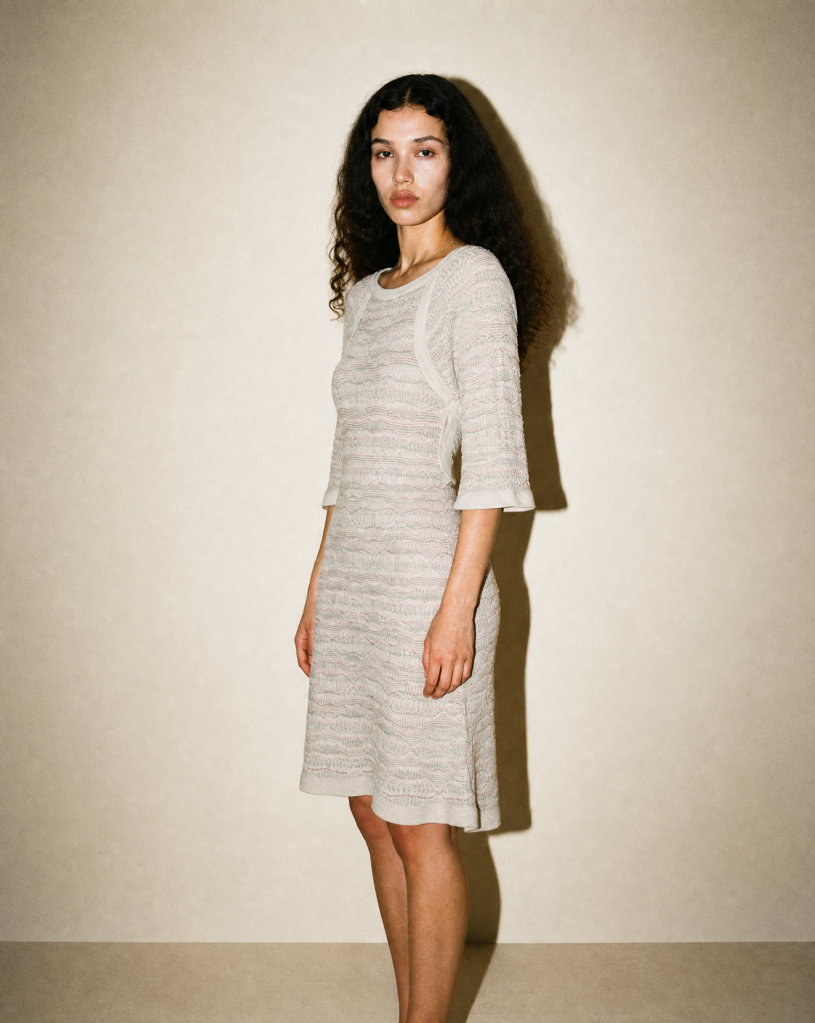 Side profile of the Chanel Dubai Tweed knit dress showing the relaxed raglan sleeves and the fluid, structured silhouette of the viscose-cotton blend.