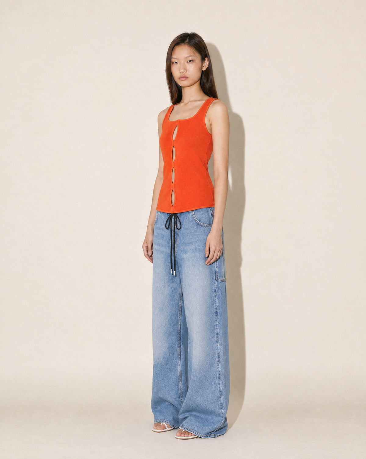 Detail of the square neckline and sculpted waist on this coral Gianni Versace stretch-knit top. Discover collectible 1990s Versace at Mezzanotte Vintage in Madrid.