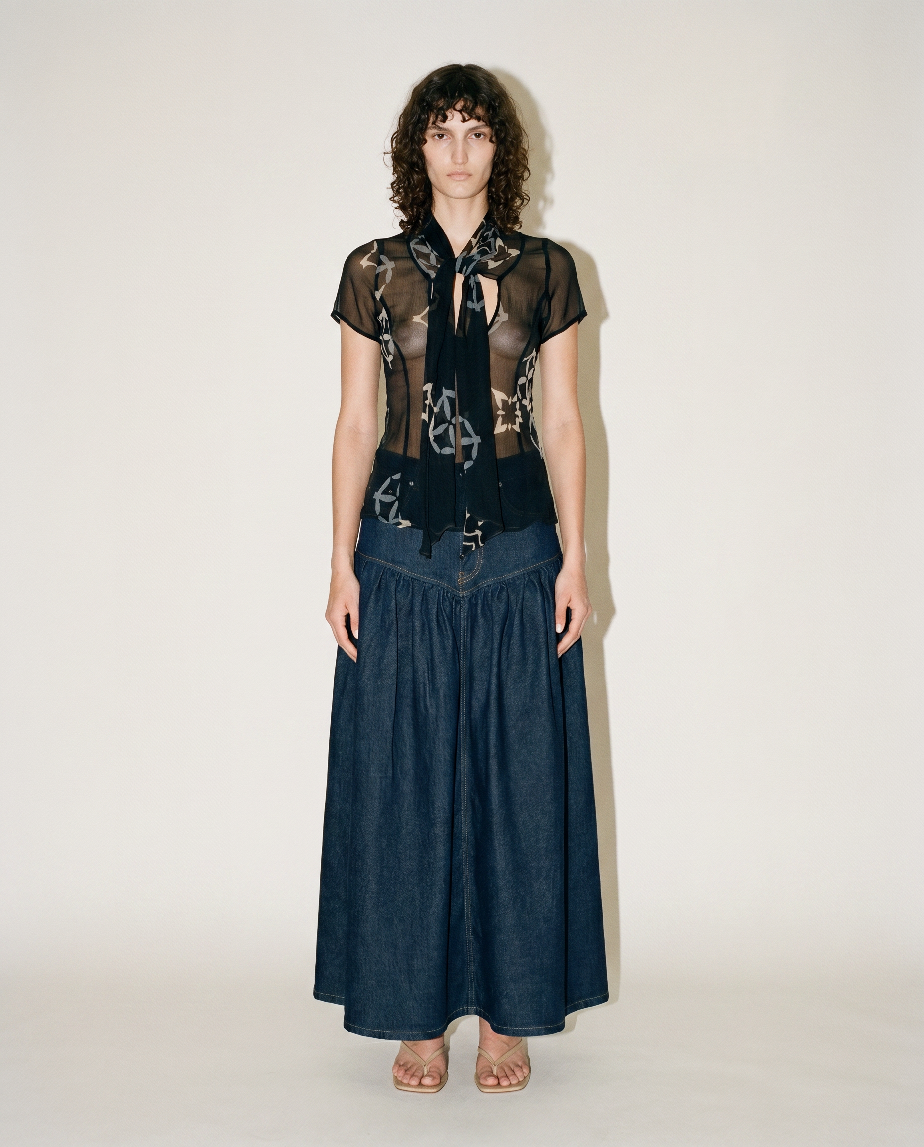 Vintage Armani Collezioni sheer black silk chiffon blouse with abstract floral print and draped scarf neckline, available for purchase and luxury rental across Europe from Mezzanotte.
