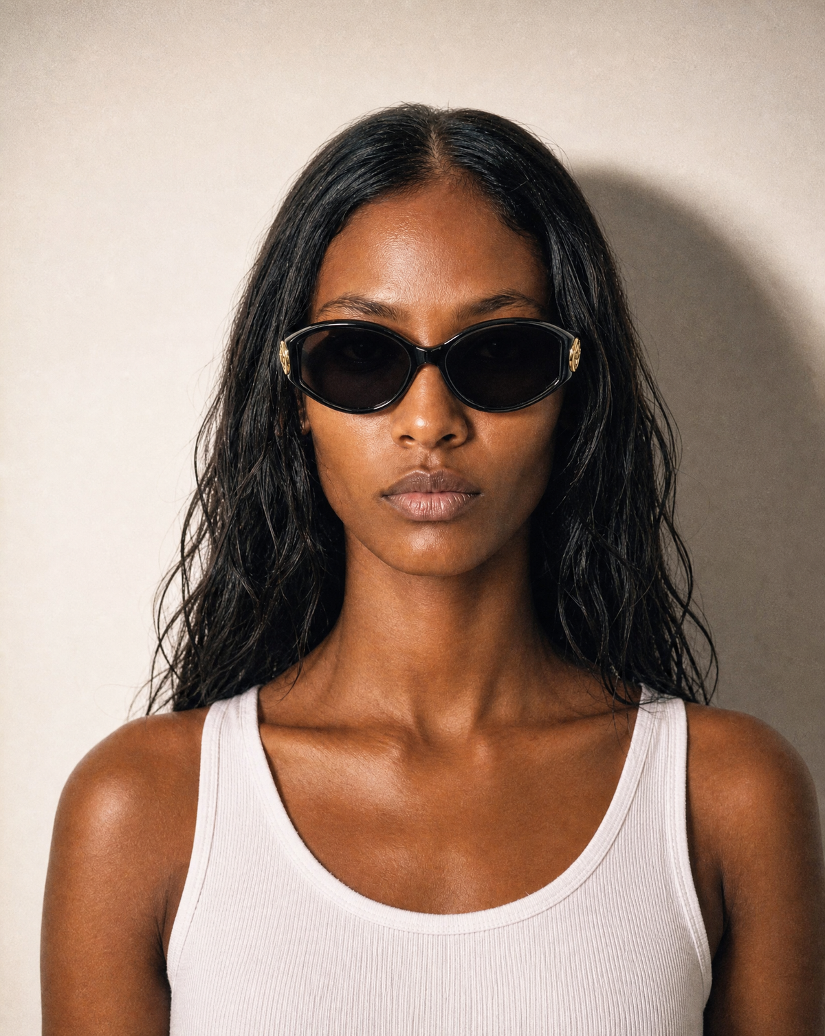 Model wearing vintage Christian Dior black oval sunglasses with gold-tone CD logo hardware.