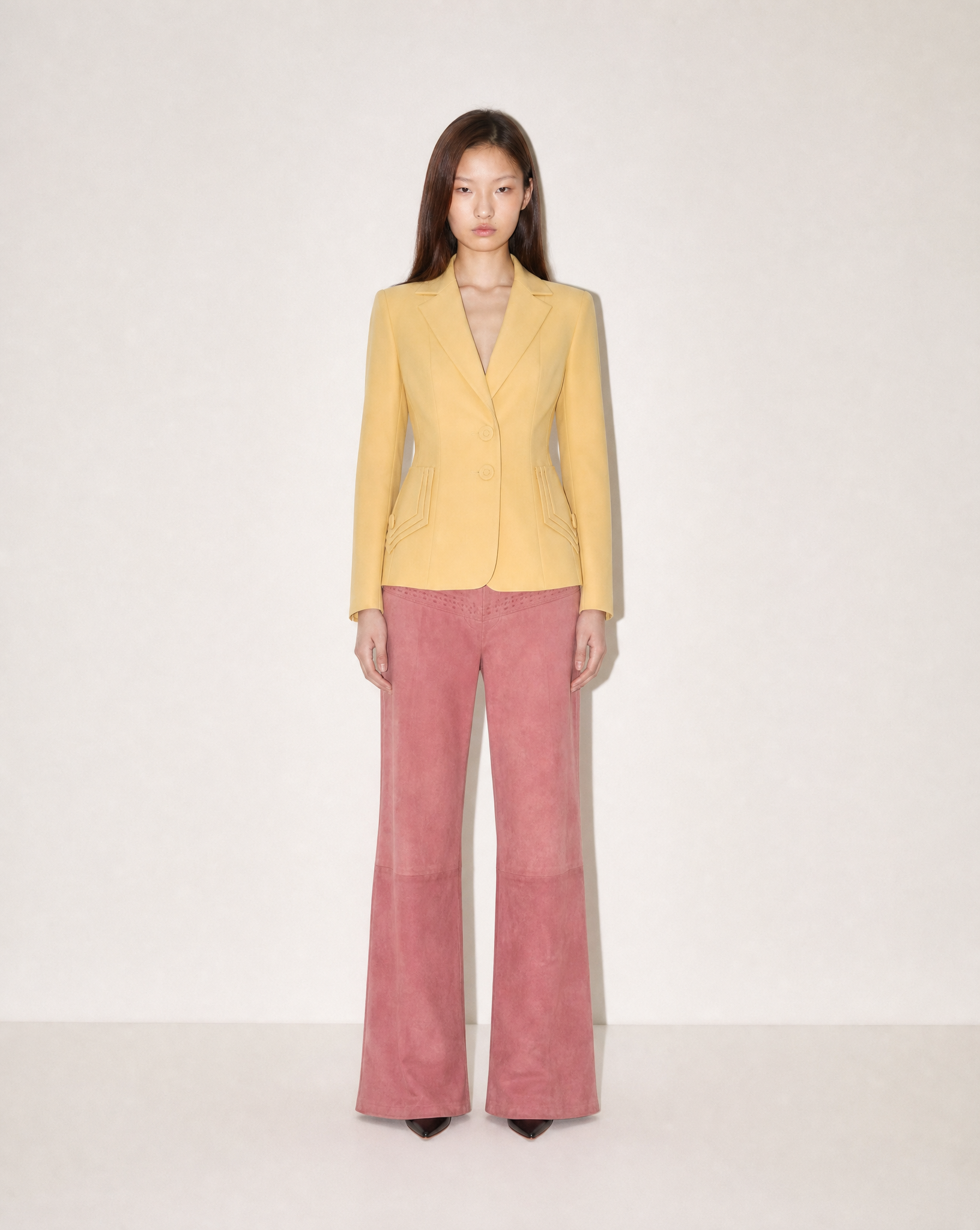 Vintage Norma Kamali pastel yellow tailored blazer with sculptural waist and geometric pocket detailing, available for purchase and luxury rental across Europe from Mezzanotte.

